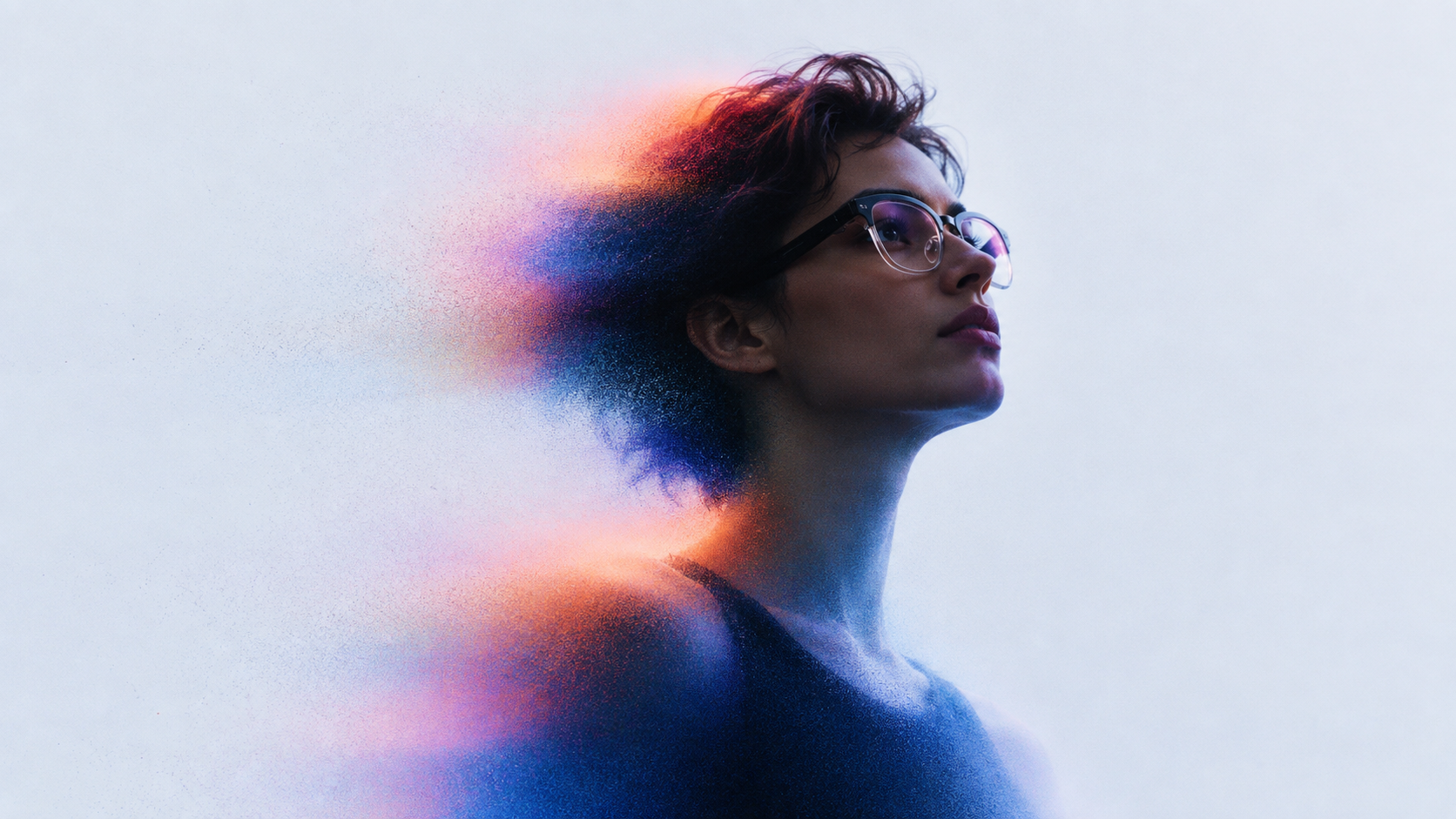 Portrait of a person wearing glasses, with the figure dissolving into violet and orange particles against a pale background.